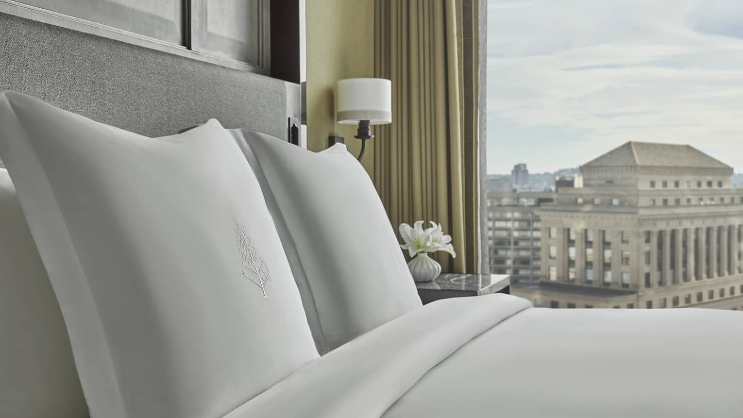 The bed is made with white linens in the Executive Suite