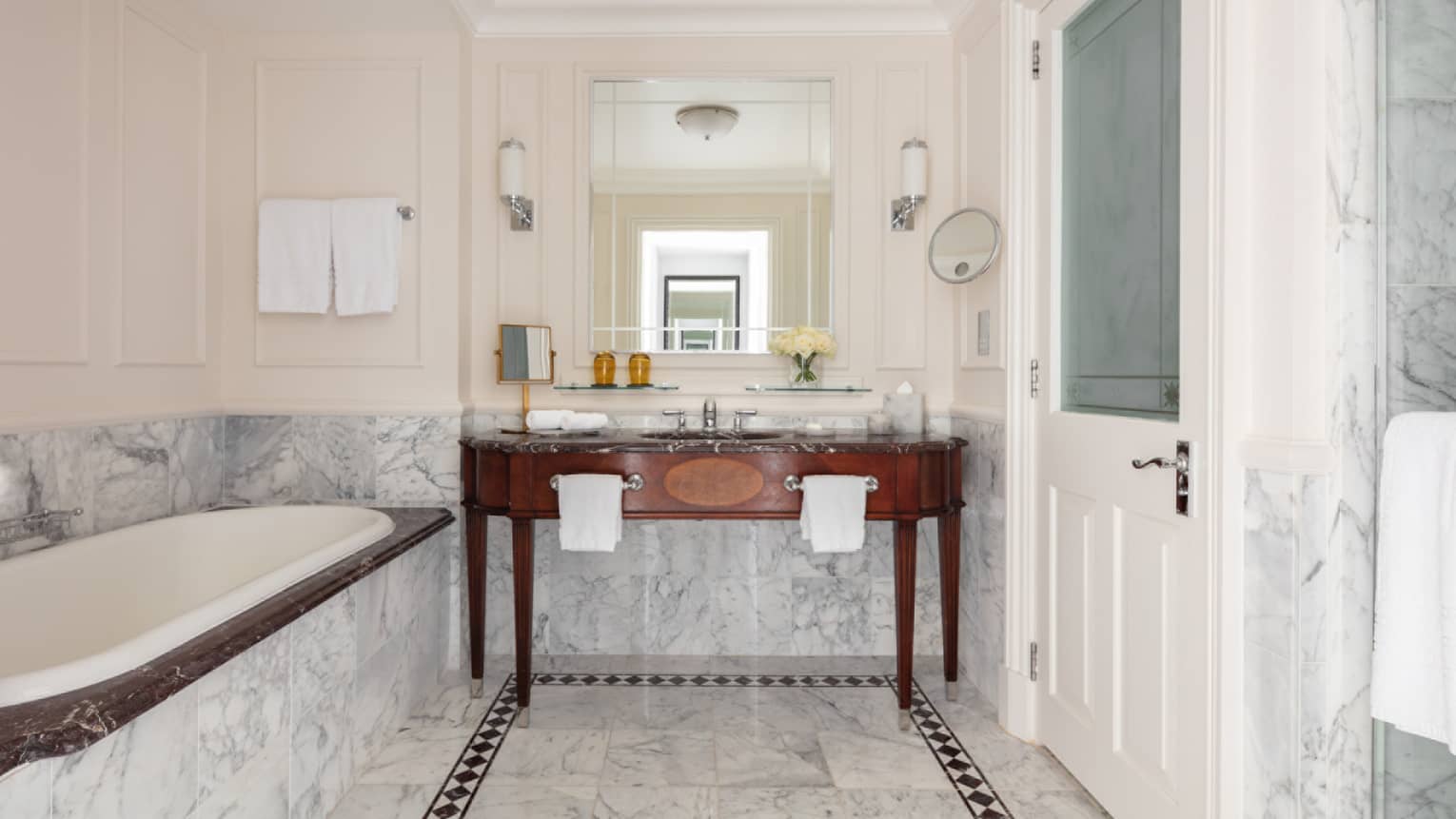 Bathroom with marble accents, large soaking tub, double wooden vanity, mirror