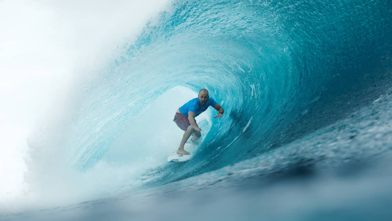 Man on surfboard surfs along large waves in remote Outer Atolls