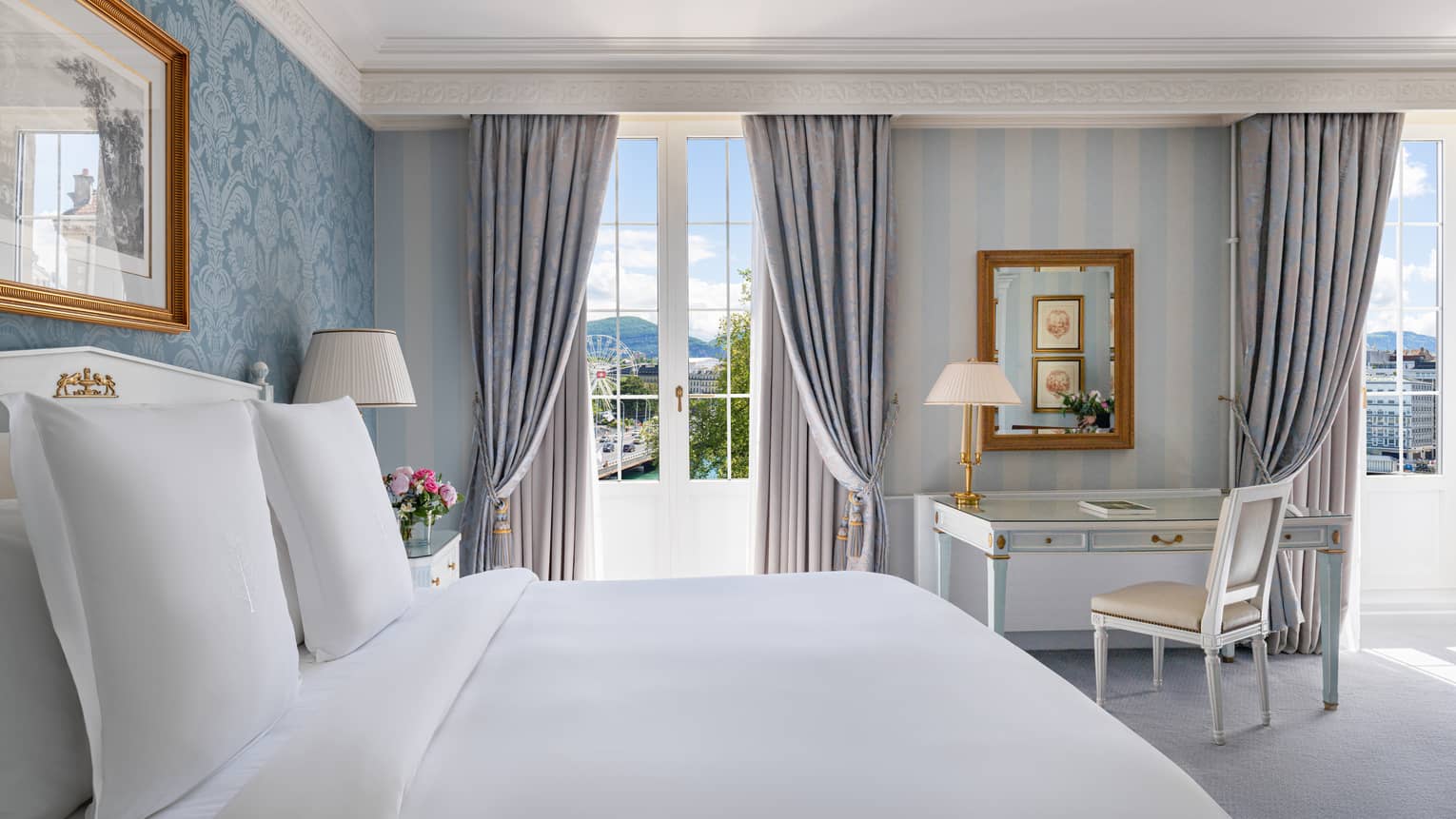 Luxury hotel room designed with blue and cream colours, and two French doors as windows, at Four Seasons Hotel des Bergues, Geneva