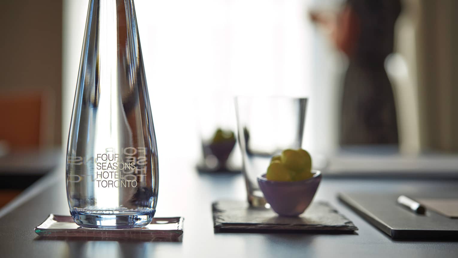 Close-up of glass water bottle, cup and agenda on meeting table