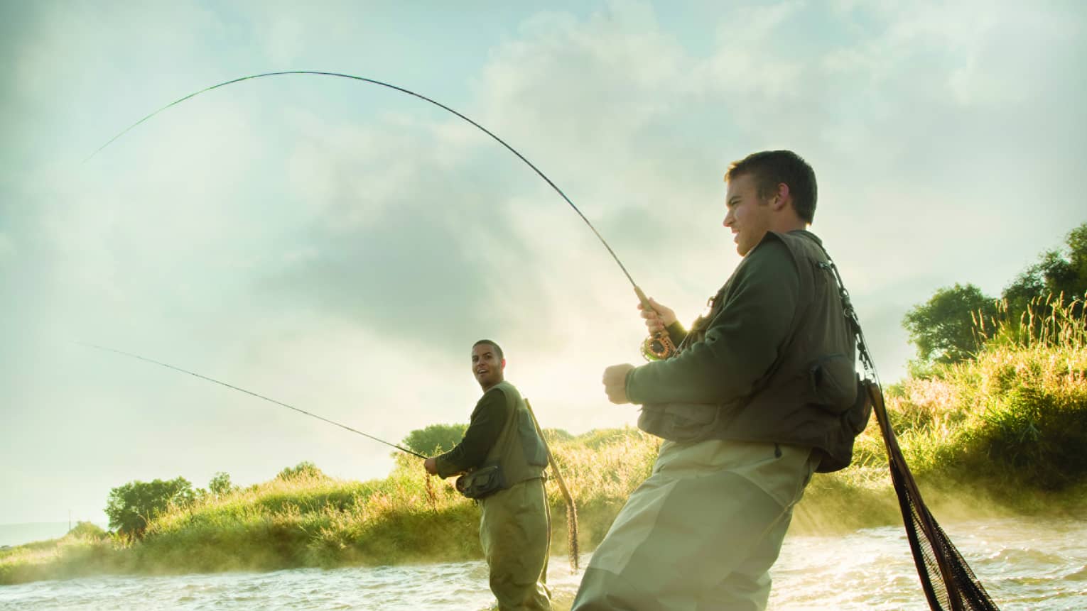 Two men standing in the water, holding rods fly fishing 