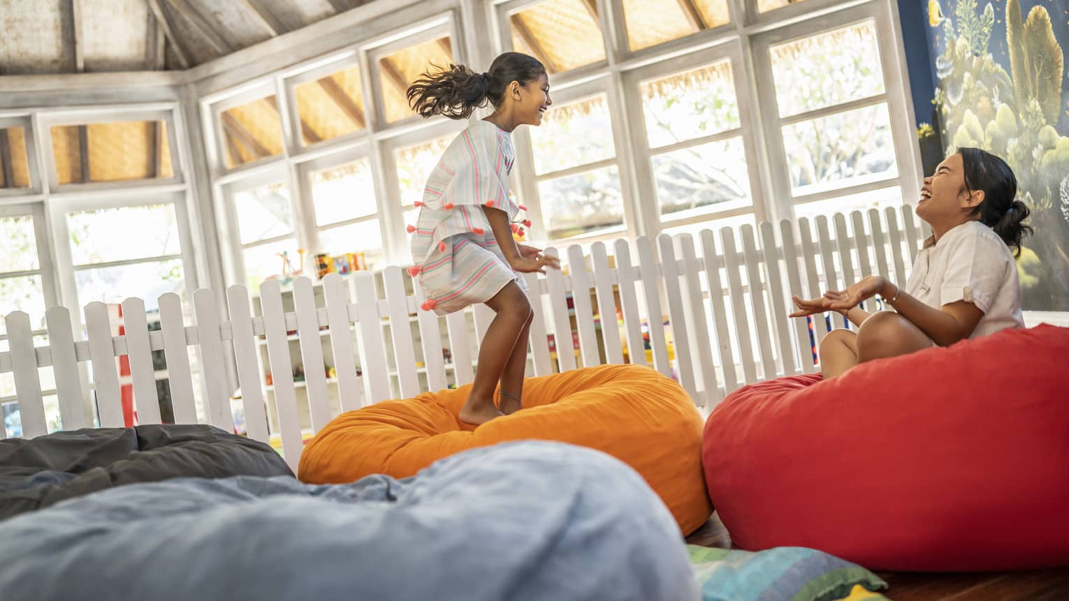 Young girl jumps on bean bag with dedicated attendant in the Kids Club