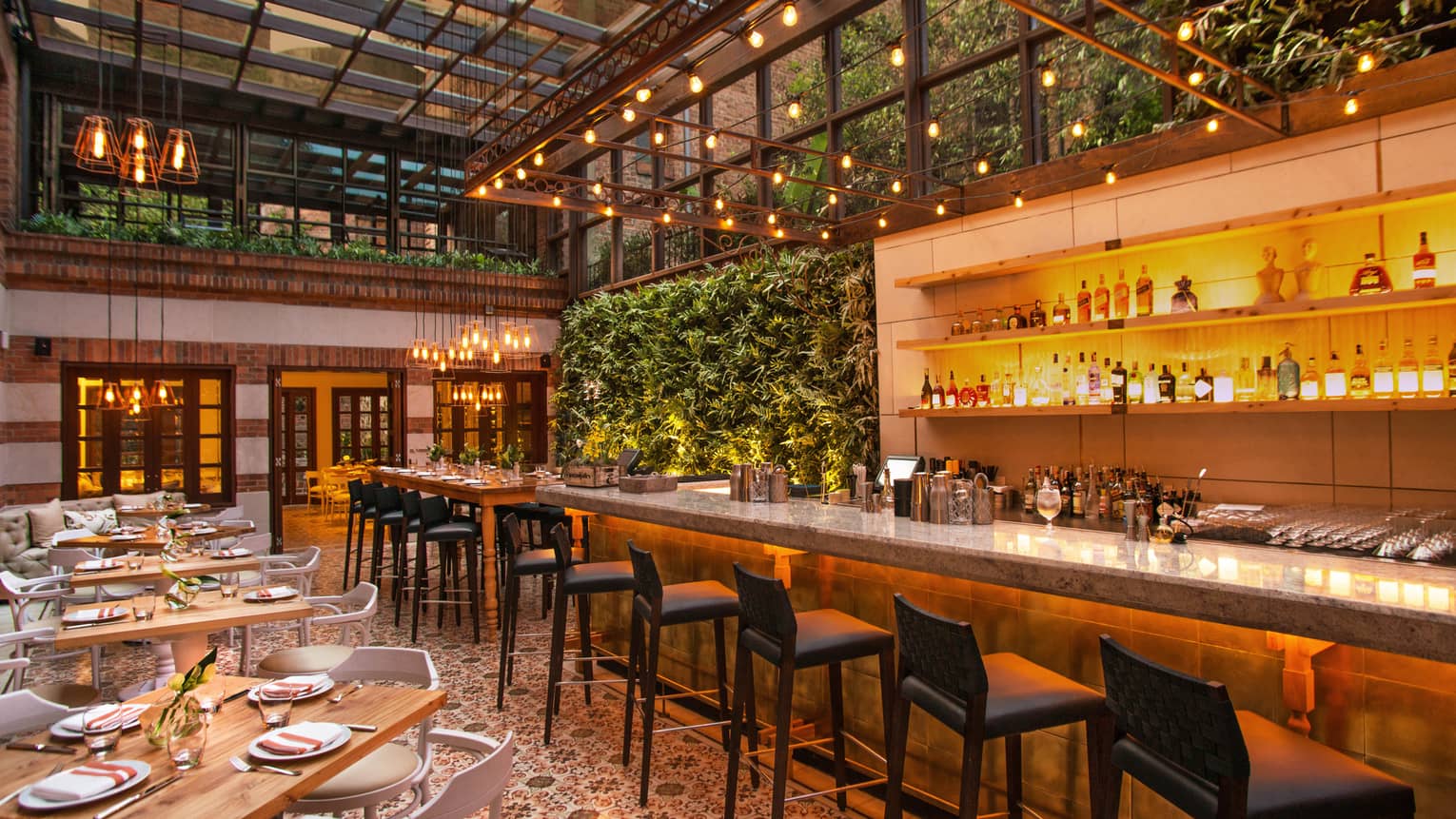 Castanyoles dining room and bar with high ceilings, Spanish-style decor, living walls with lush green plants, patio lights