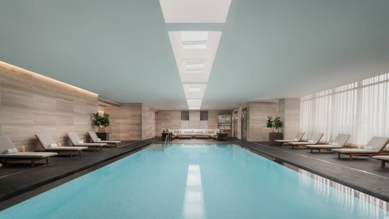 Expansive view of indoor pool lined with lounge chairs
