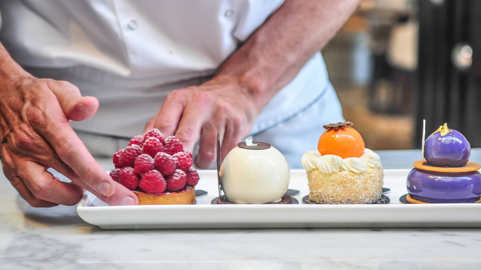 Pastry chef arranges gourmet desserts on white platter