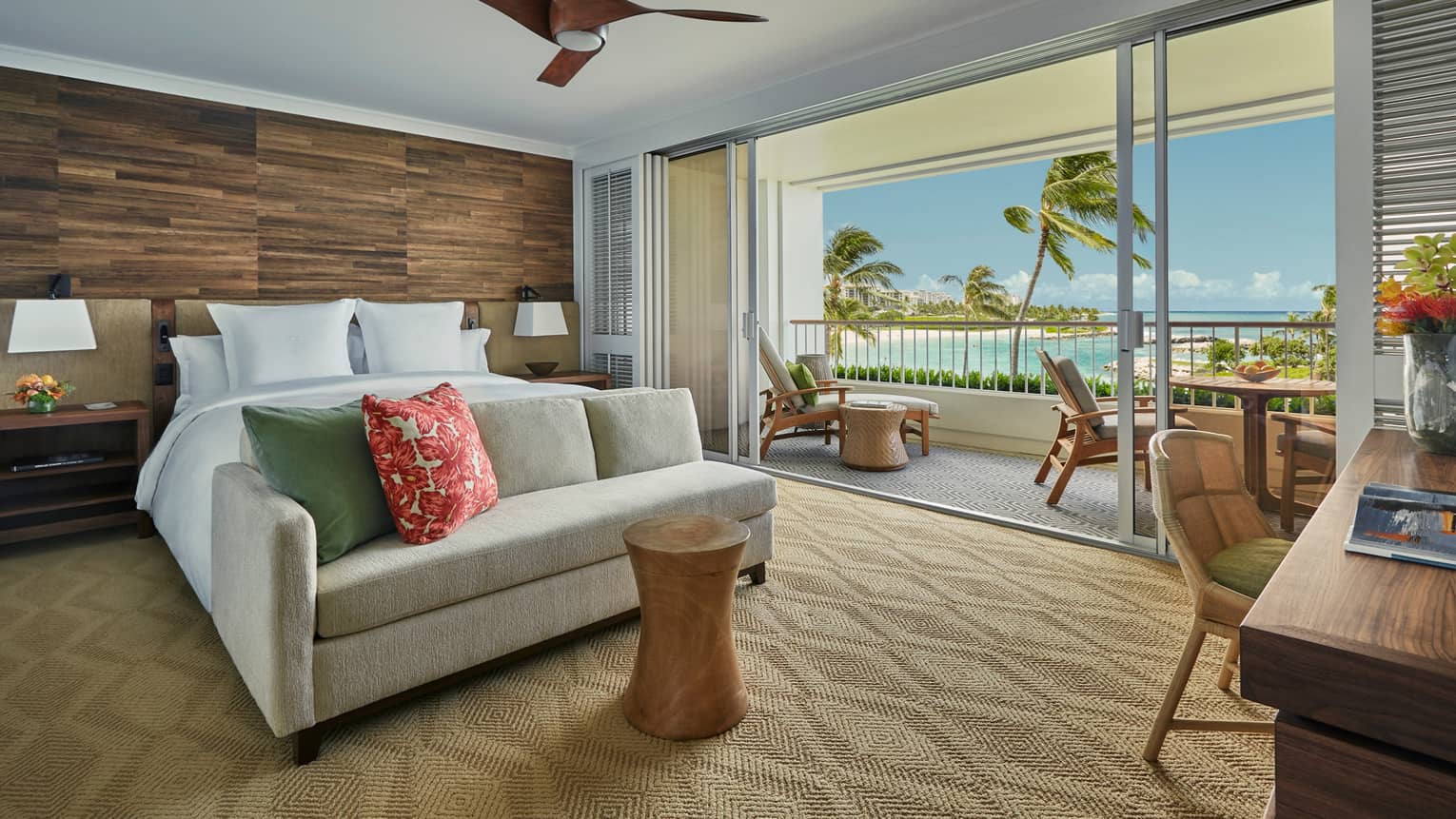 Prime Corner Oceanfront Room loveseat at foot of bed against wood grain wall, balcony wall