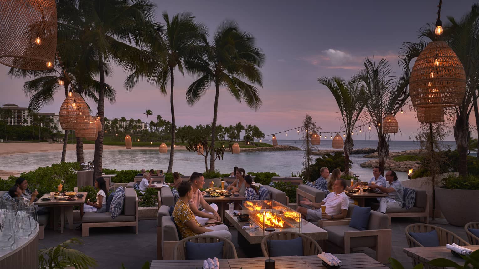 People mingling on outdoor, waterfront terrace in tropical location at night