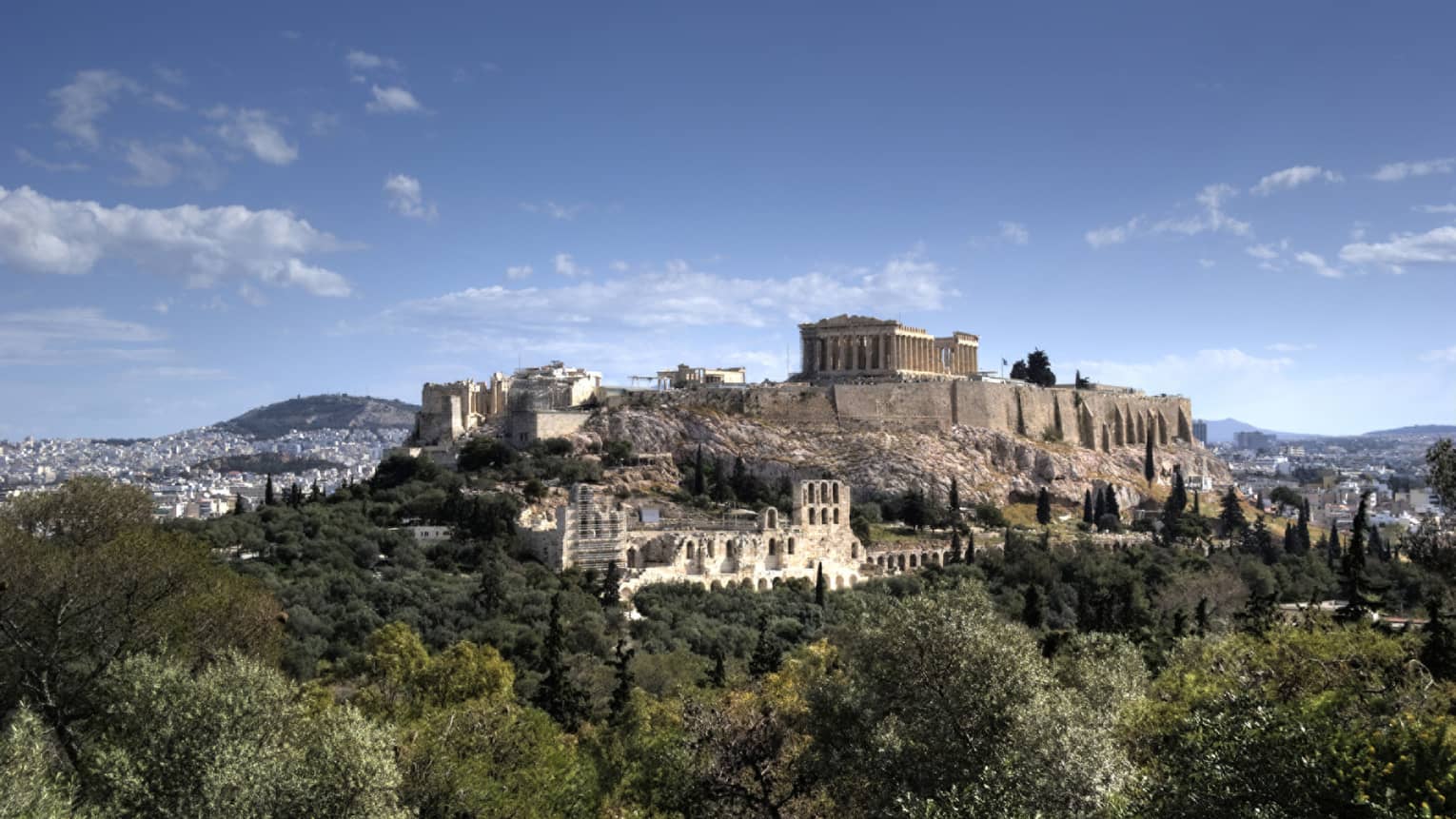 Ancient ruins of Acropolis on mountain surrounded by greenery 