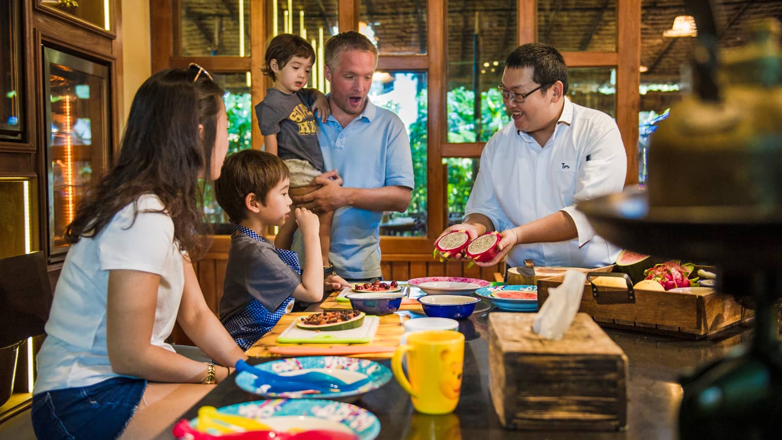 Chef presents two halves of dragon fruit to family during Thai cooking demonstration