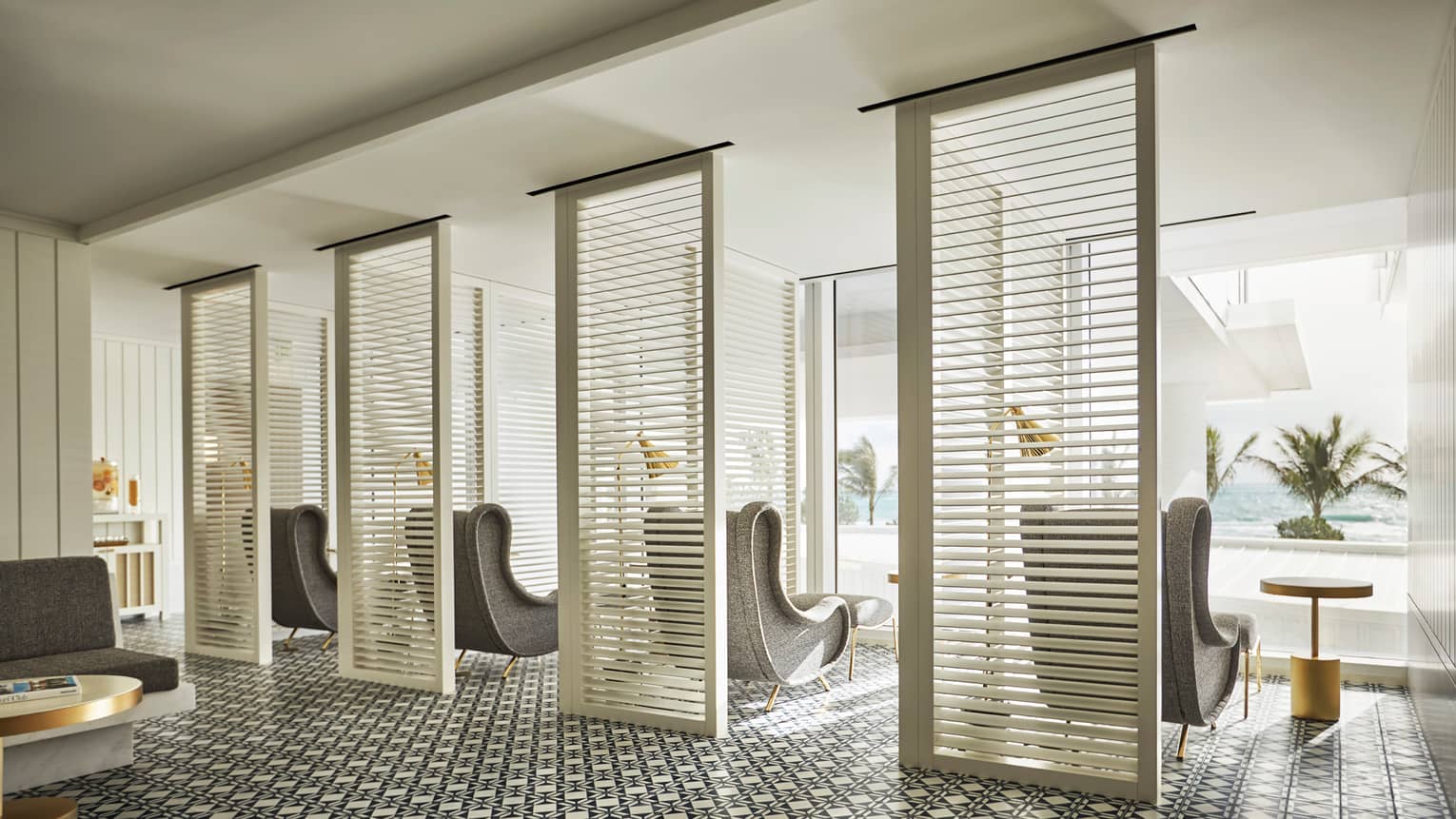 Oceanfront spa and wellness center. Retro-style grey arm chairs in front of window overlooking ocean