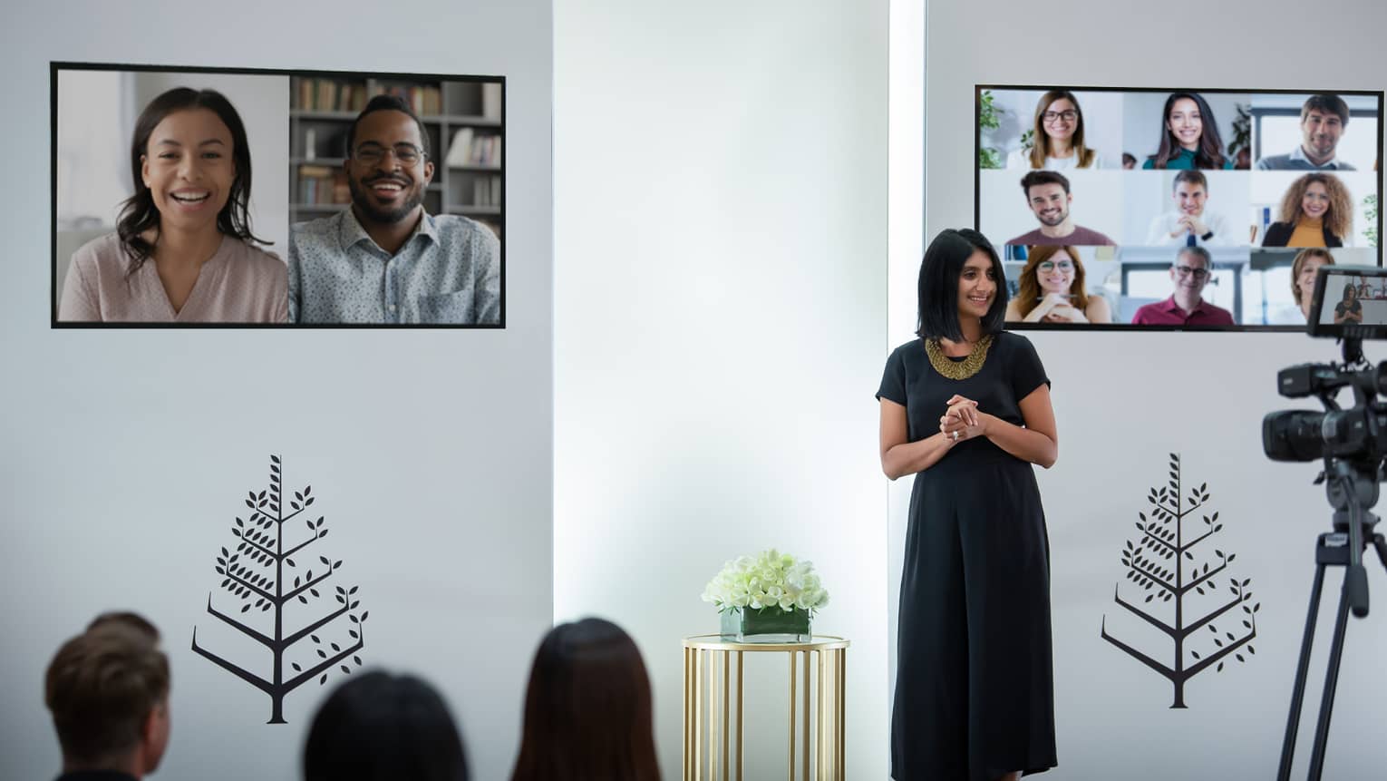 Several people host a virtual meeting in a room with the Four Seasons logo.