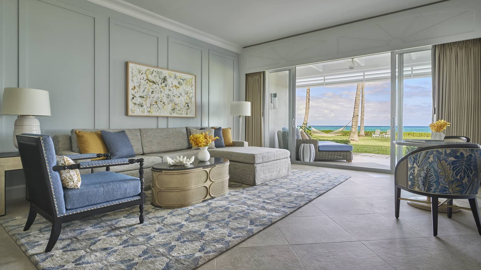 Living room with sofa, blue arm chair, rug, walk-out ocean-view terrace
