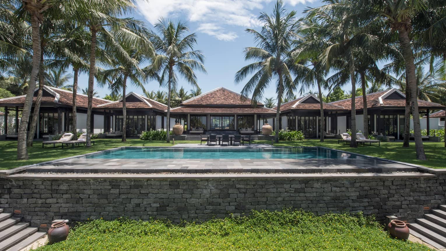 Ocean-View Villas behind large stone outdoor swimming pool, tall palm trees