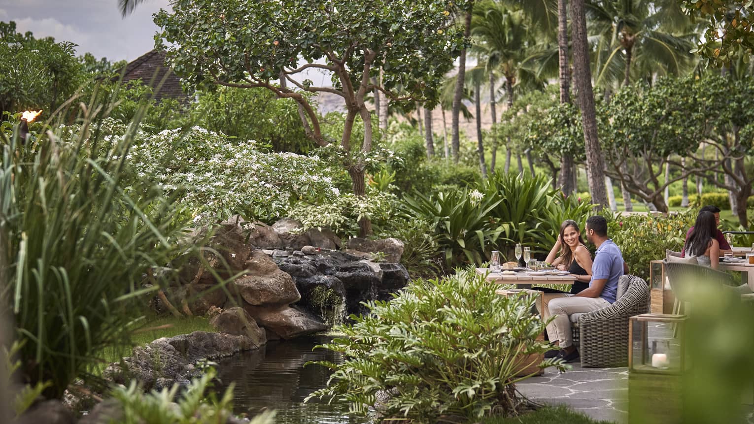 Couple sitting at table surrounded by lush greenery at contemporary outdoor restaurant