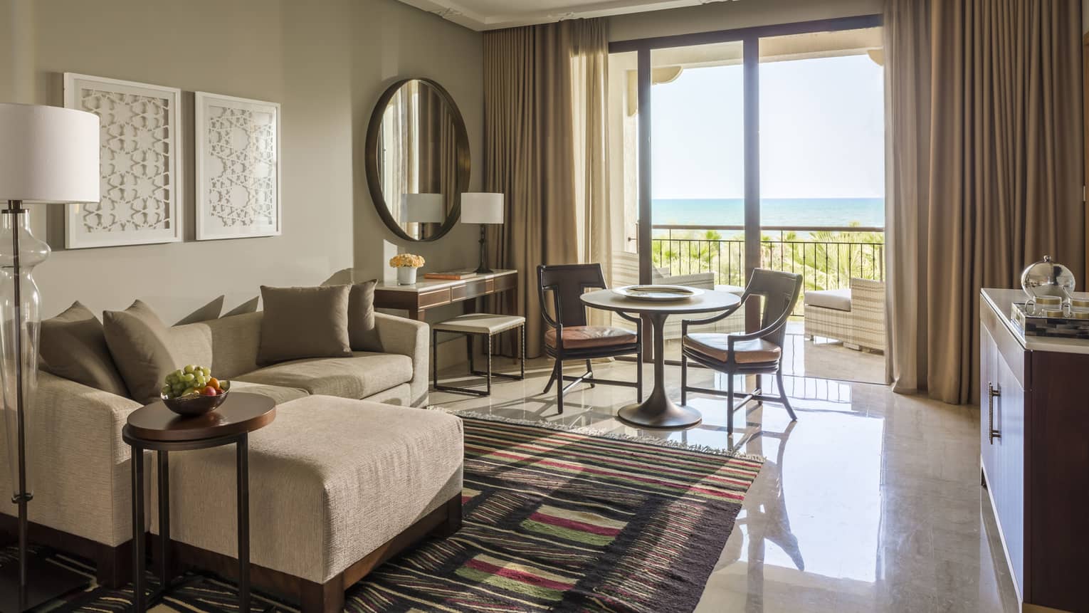 Deluxe Sea View hotel room with modular sofa, small table and chairs by sunny balcony doors