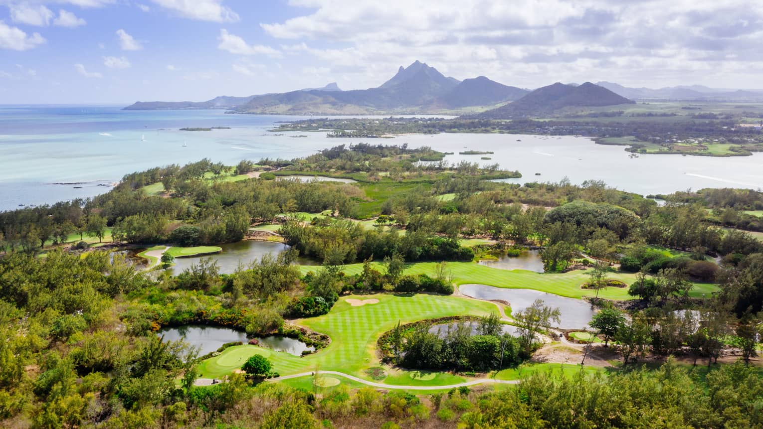 Aerial view of golf course with Indian Ocean and mountains in backdrop