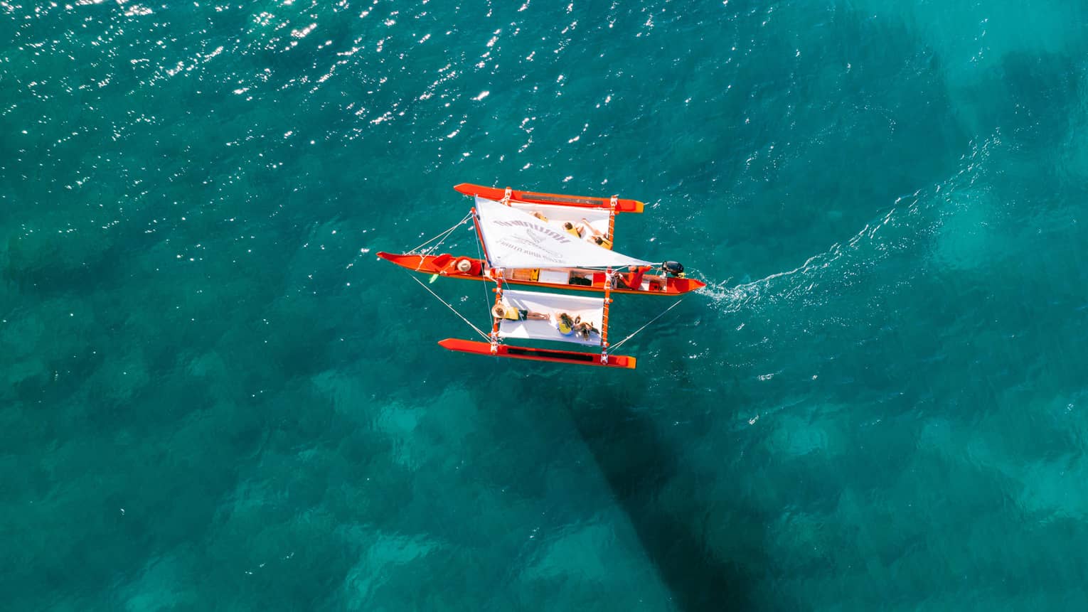 Aerial view of red and white boat surrounded by clear blue water