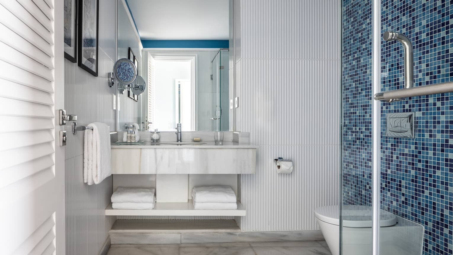 Suite bathroom with walk in shower, blue tiled wall, double vanity, mirror