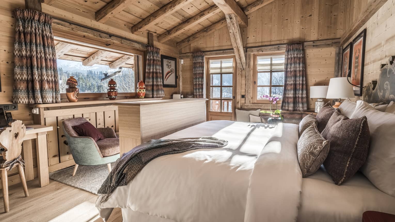 Sunny Suite Alpage room with wood, wool and tweed decor, bed, chairs near bright windows 