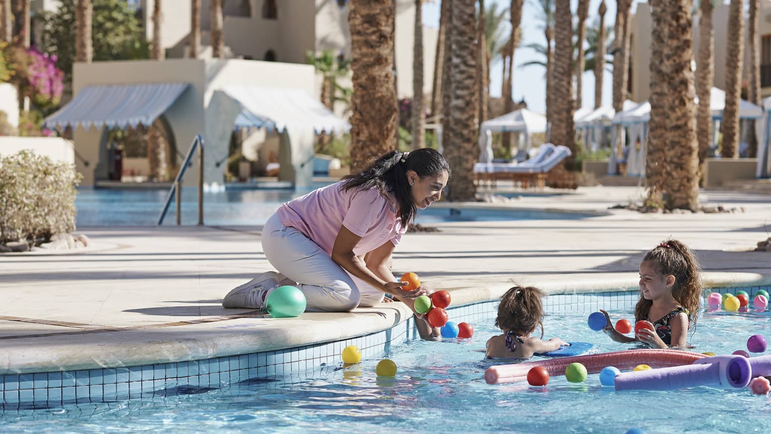 Woman supervising two children in pool with pool toys