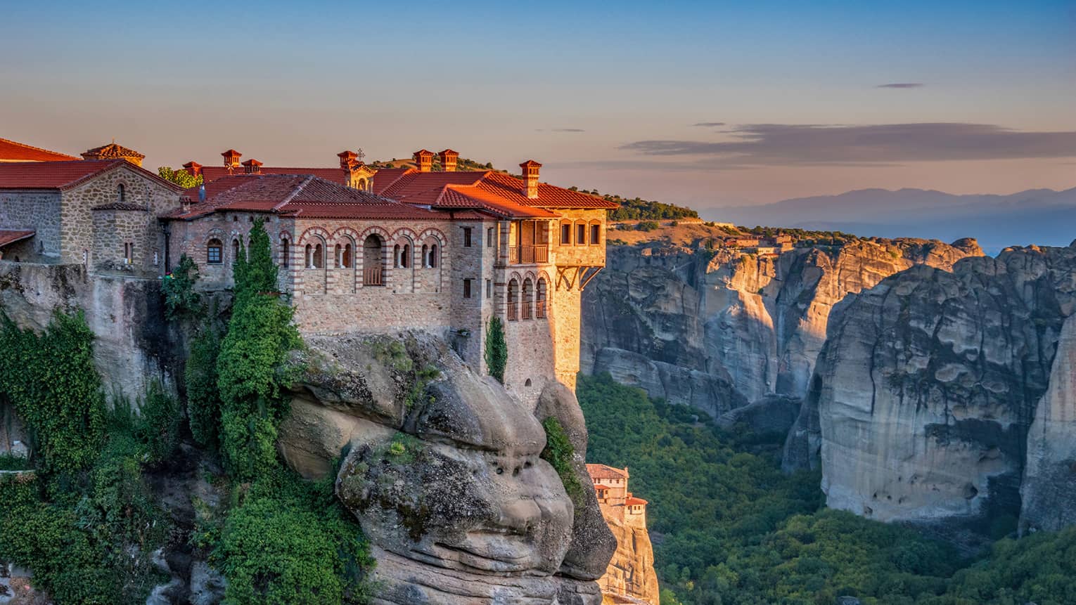 Ancient monastery on top of rock formation at sunset