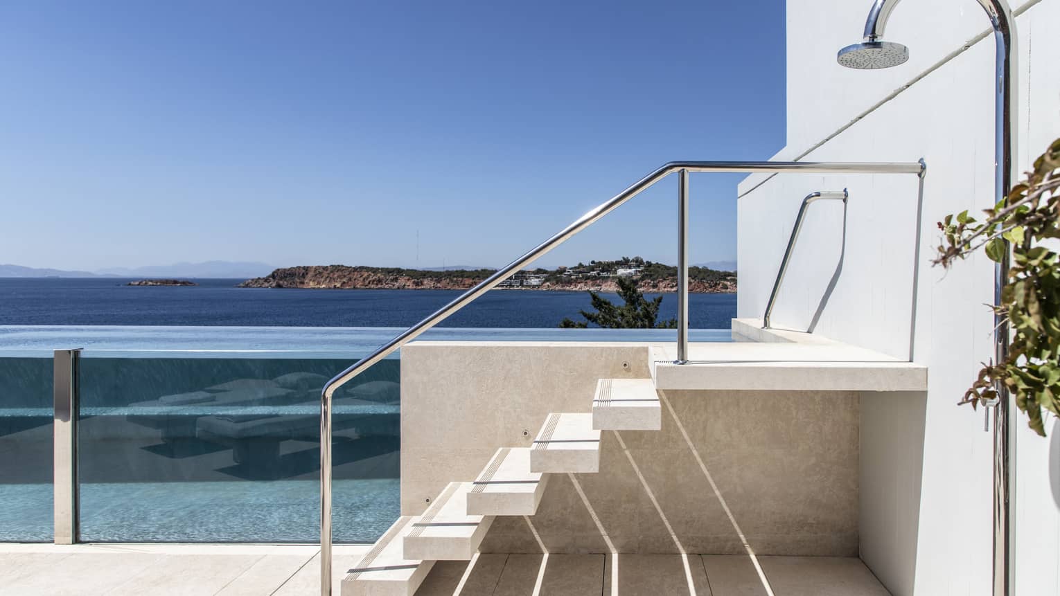 Six stairs lead to entrance of a raised, glass-enclosed pool on private patio with sea view