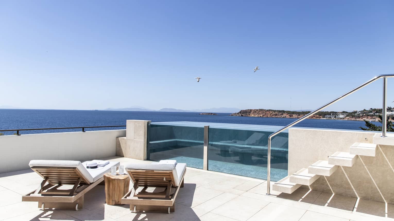 Raised, glass-enclosed pool on a private terrace with two chaise lounges