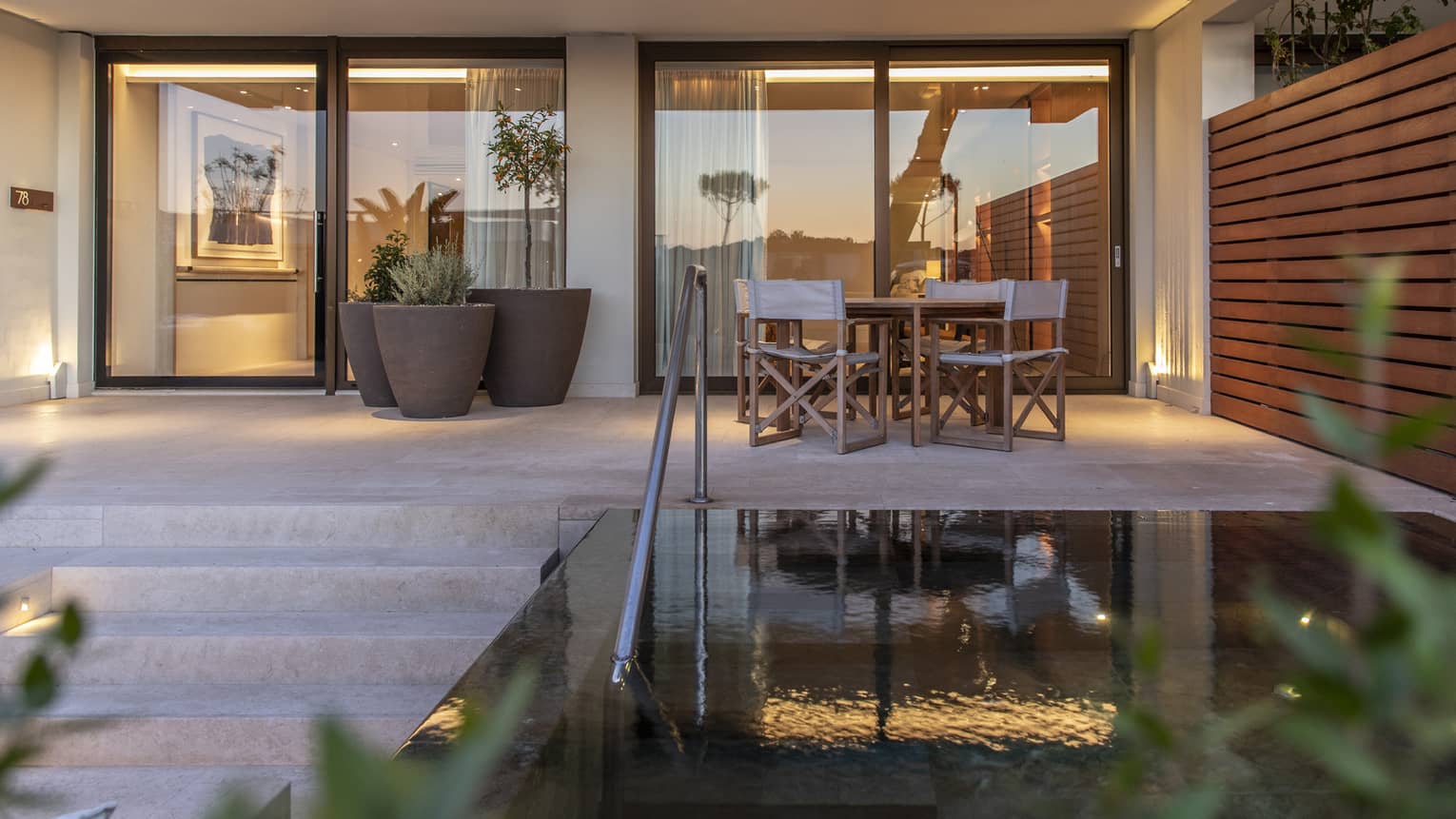 Private terrace at dusk with plunge pool, dining table for four, wooden privacy wall
