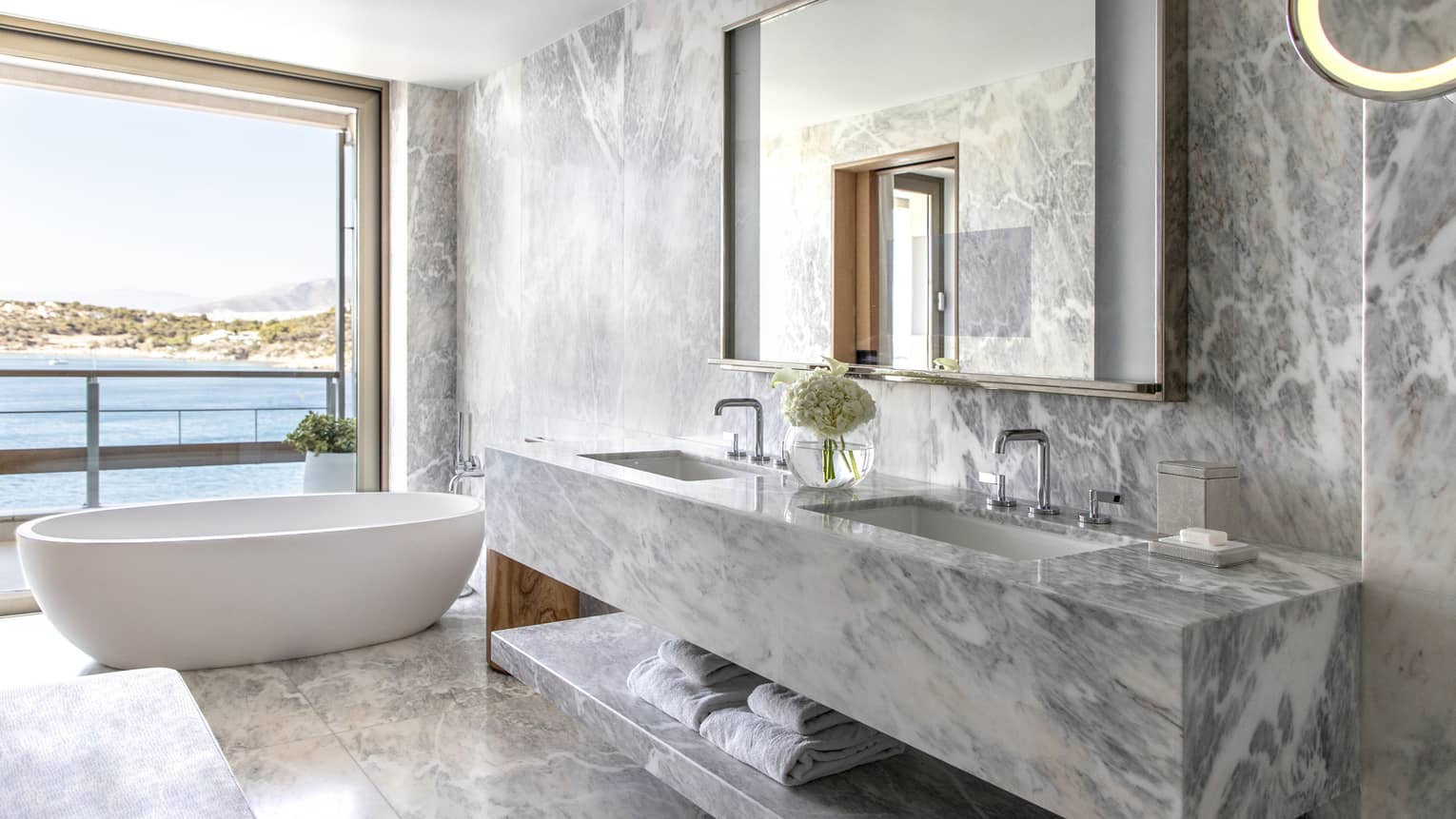 Bathroom with marble wall, vanity and floors, tub, open wall to the sea