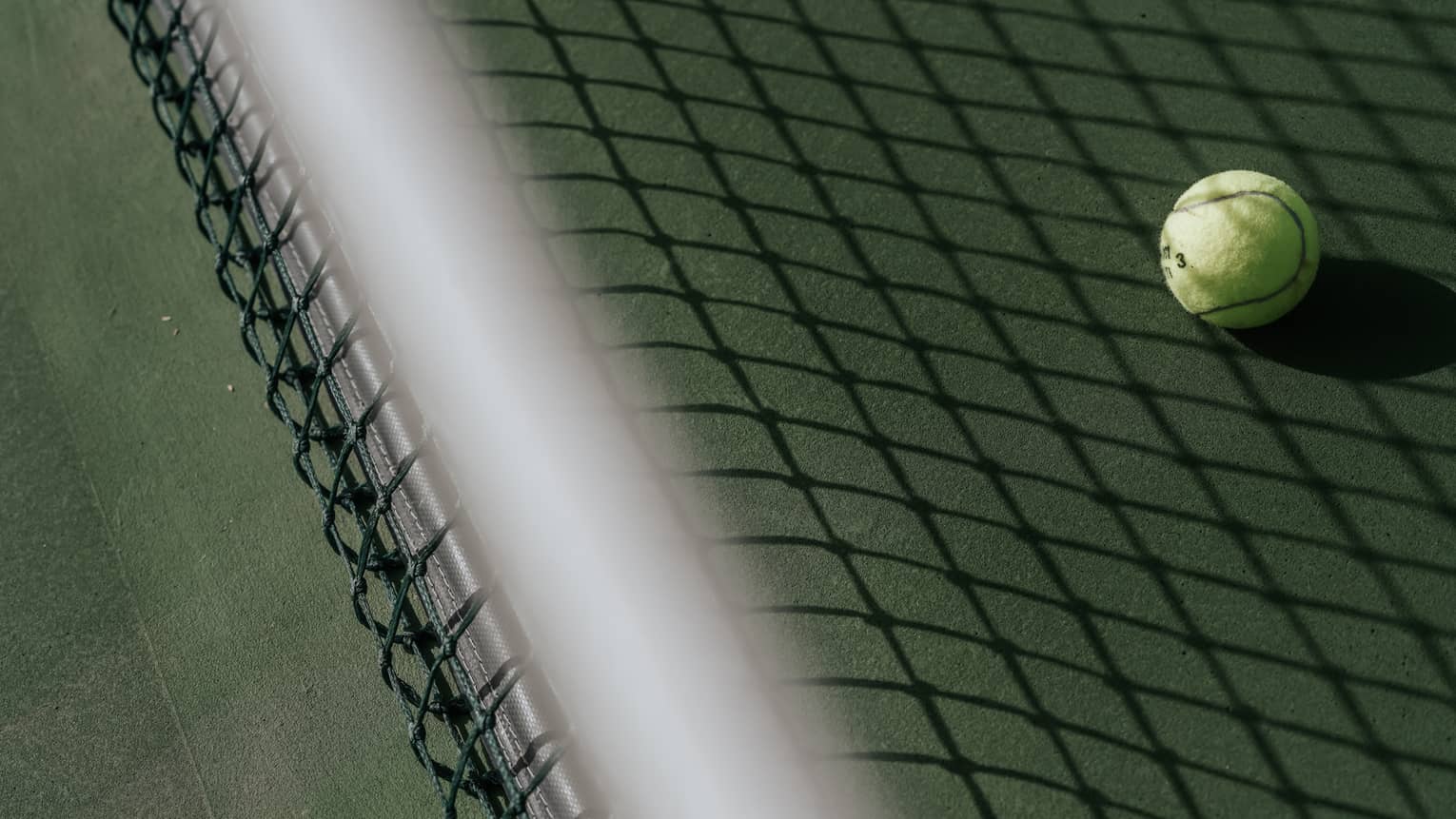 Tennis ball on tennis court with shadow of net