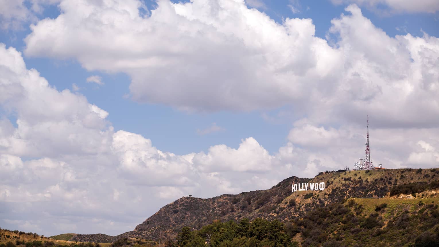 Hollywood sign on green Los Angeles hills against blue sky
