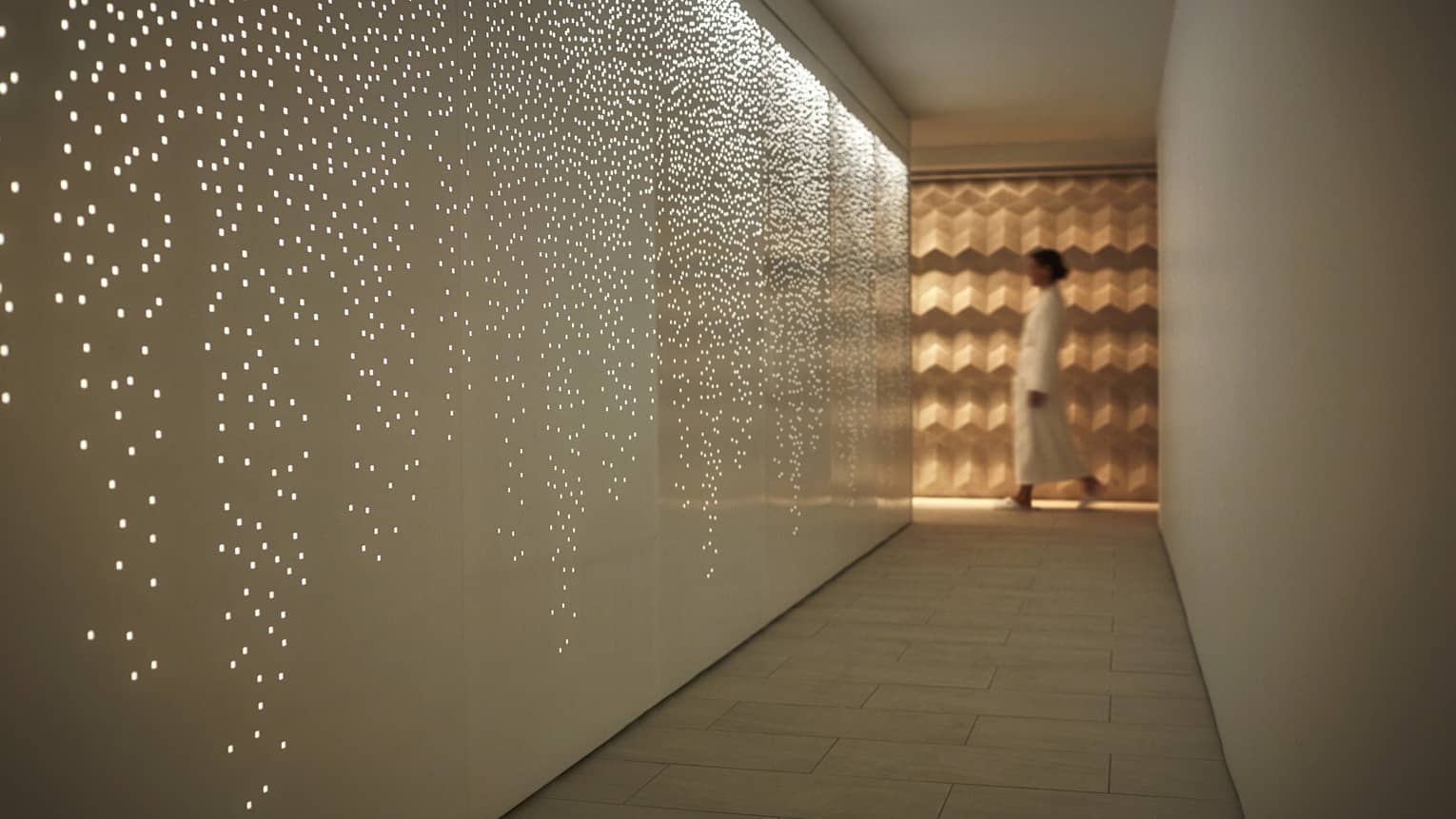 Dimly-lit spa hallways with star-speckled walls, woman in white robe walking