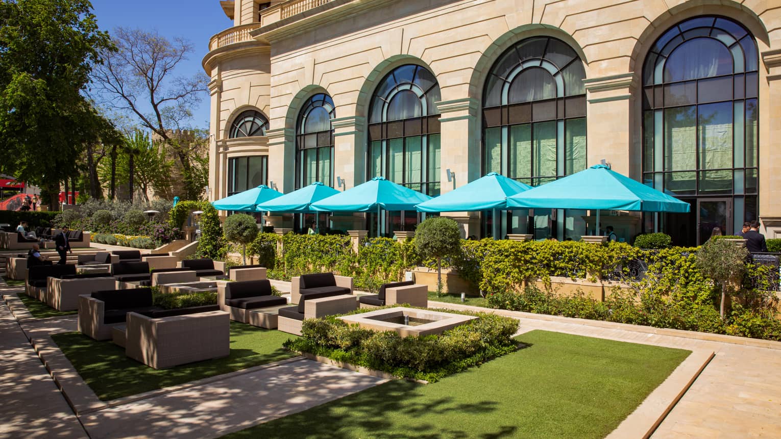 Eyvan Terrace dining area with shaded lounge and tables with aqua-blue umbrellas