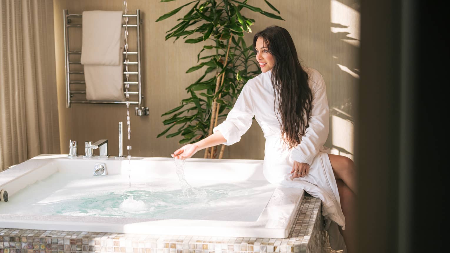 Woman sits at side of spa hot tub with spa robe on