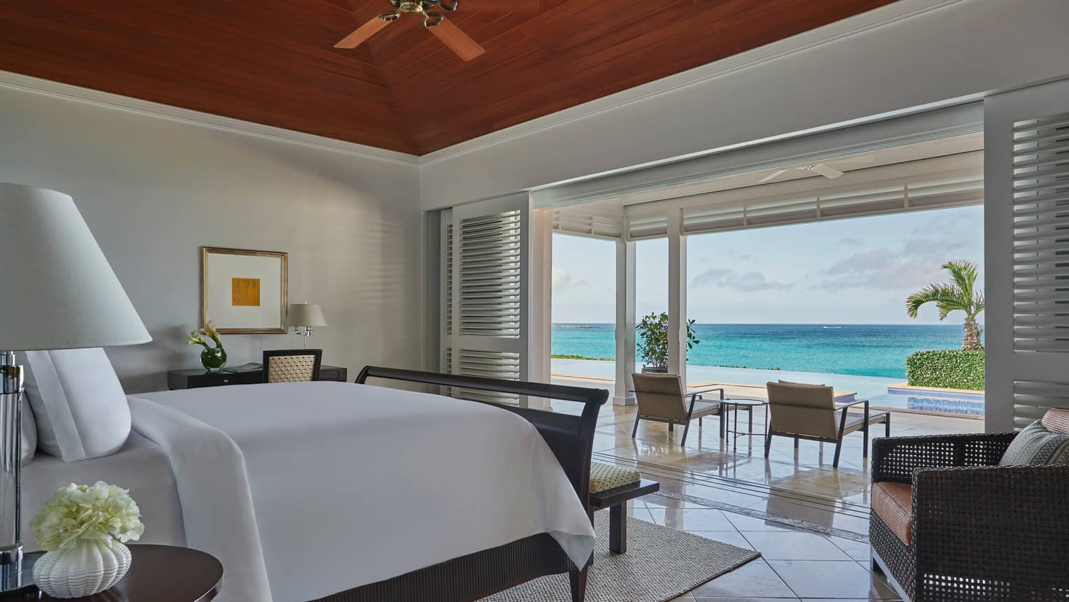 Hotel bed across from open wall to patio overlooking white sand beach, oceanfront