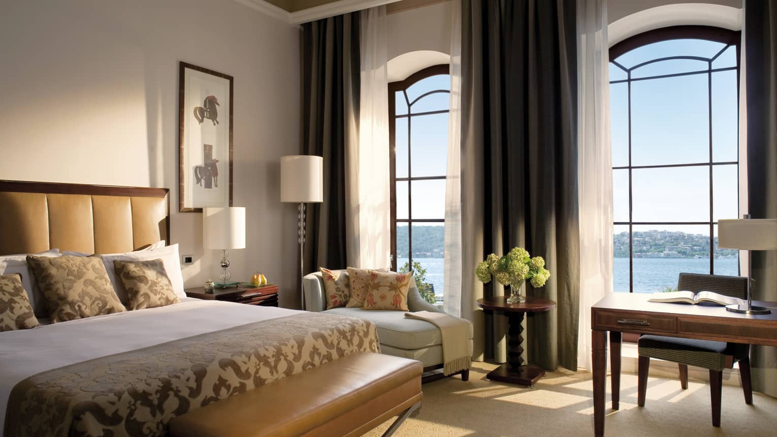 The Palace Bosphorus Room bed with padded brown headboard, bench, sunny bay windows with sea views