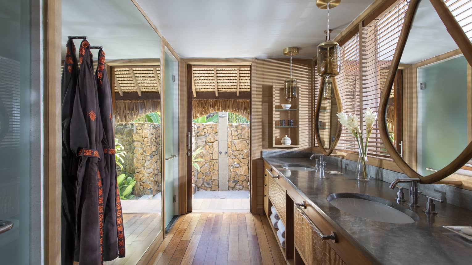 Double vanity sinks in an indoor-outdoor villa bathroom, with teak floors