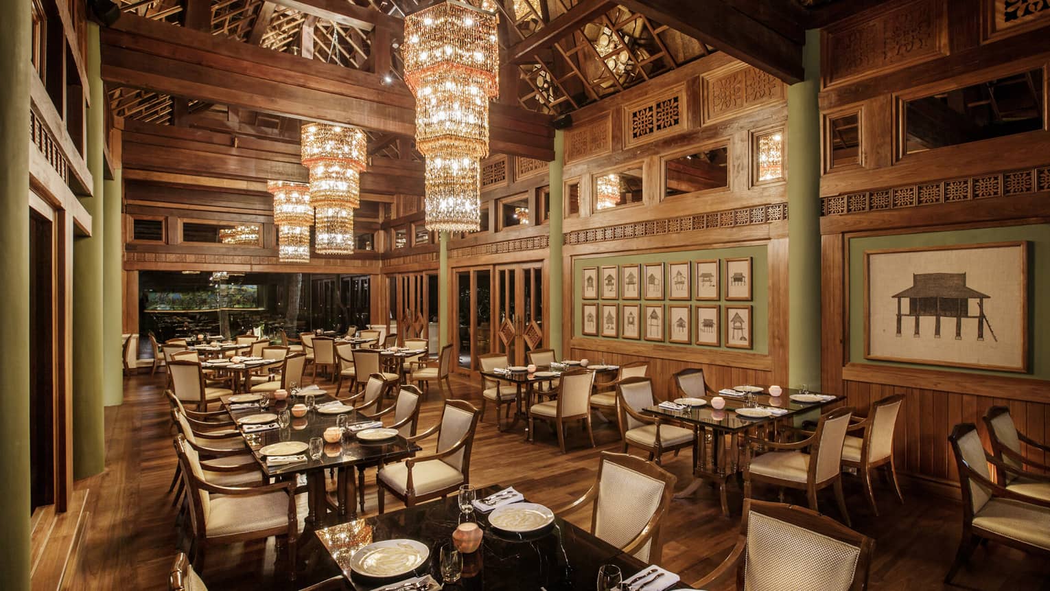 Long crystal chandeliers hang from high ceilings over KHAO indoor dining room with wood decor