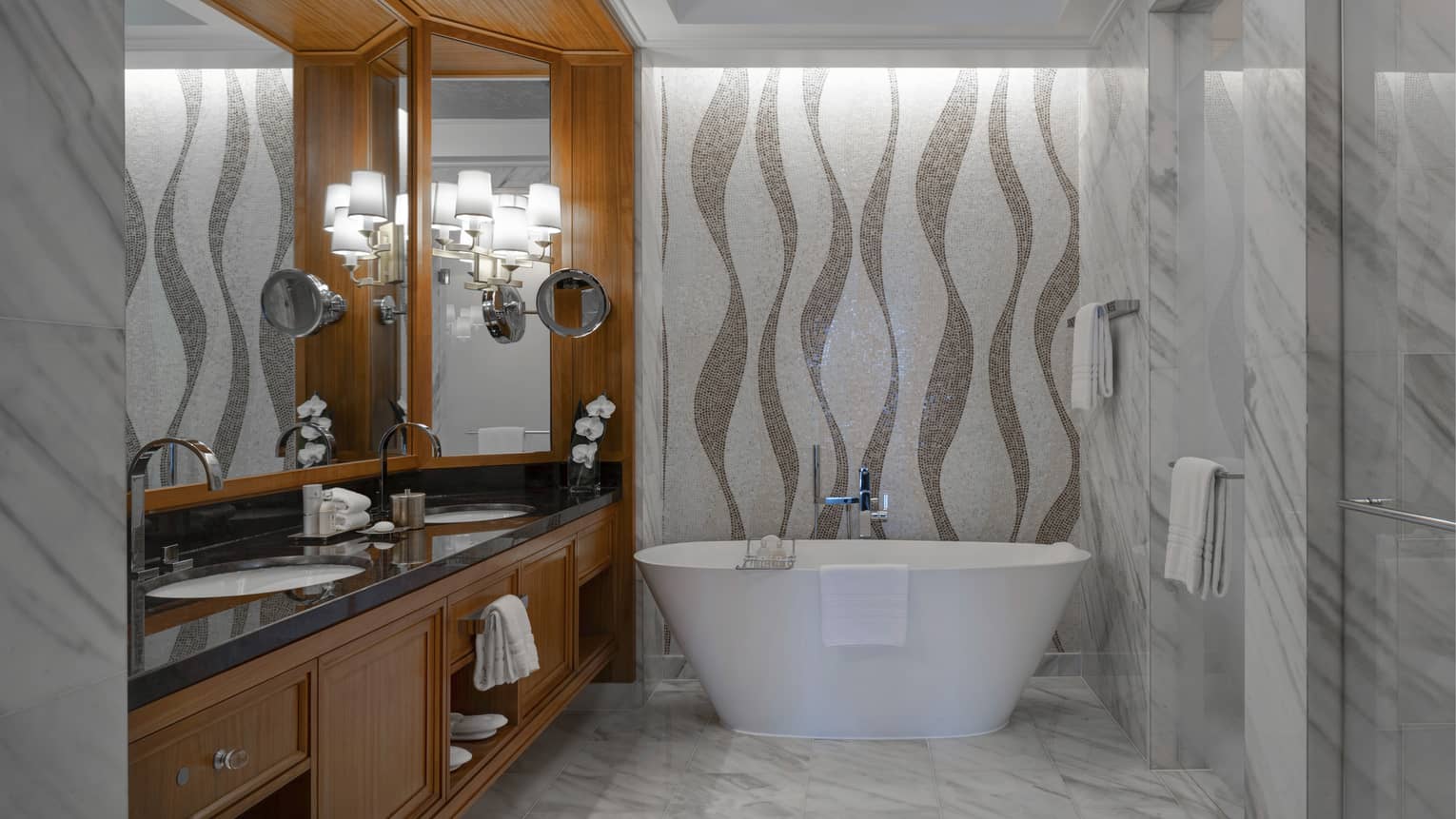 Bathroom with marble floors, mosaic tile wall, freestanding tub, wooden vanity