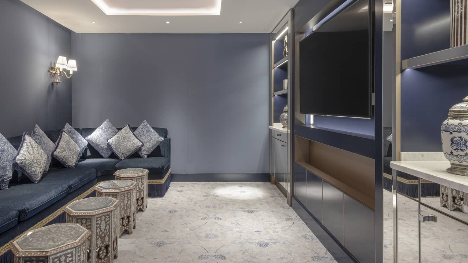 Modern private media room with blue walls, dark blue sofa and entertainment centre