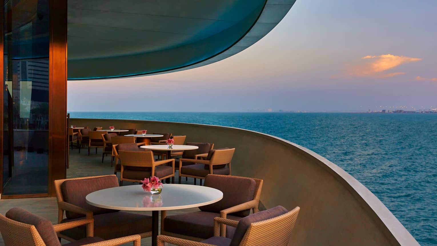 Dining tables on curved patio of Noby Restaurant, overlooking blue sea