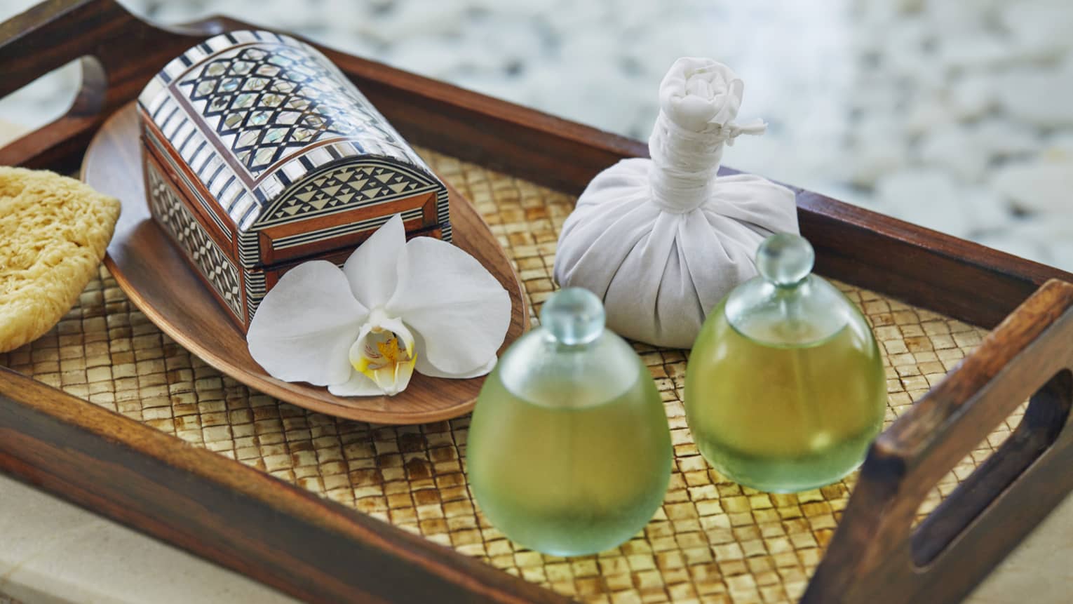 Wood tray with glass spa bottles, oils, small decorative box and white flower