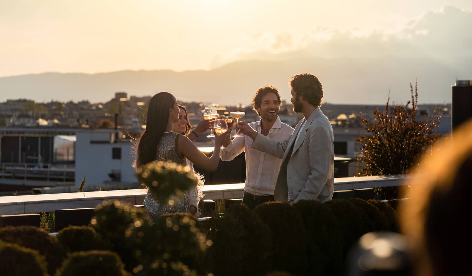 Four friends toasting on rooftop terrace at sunset