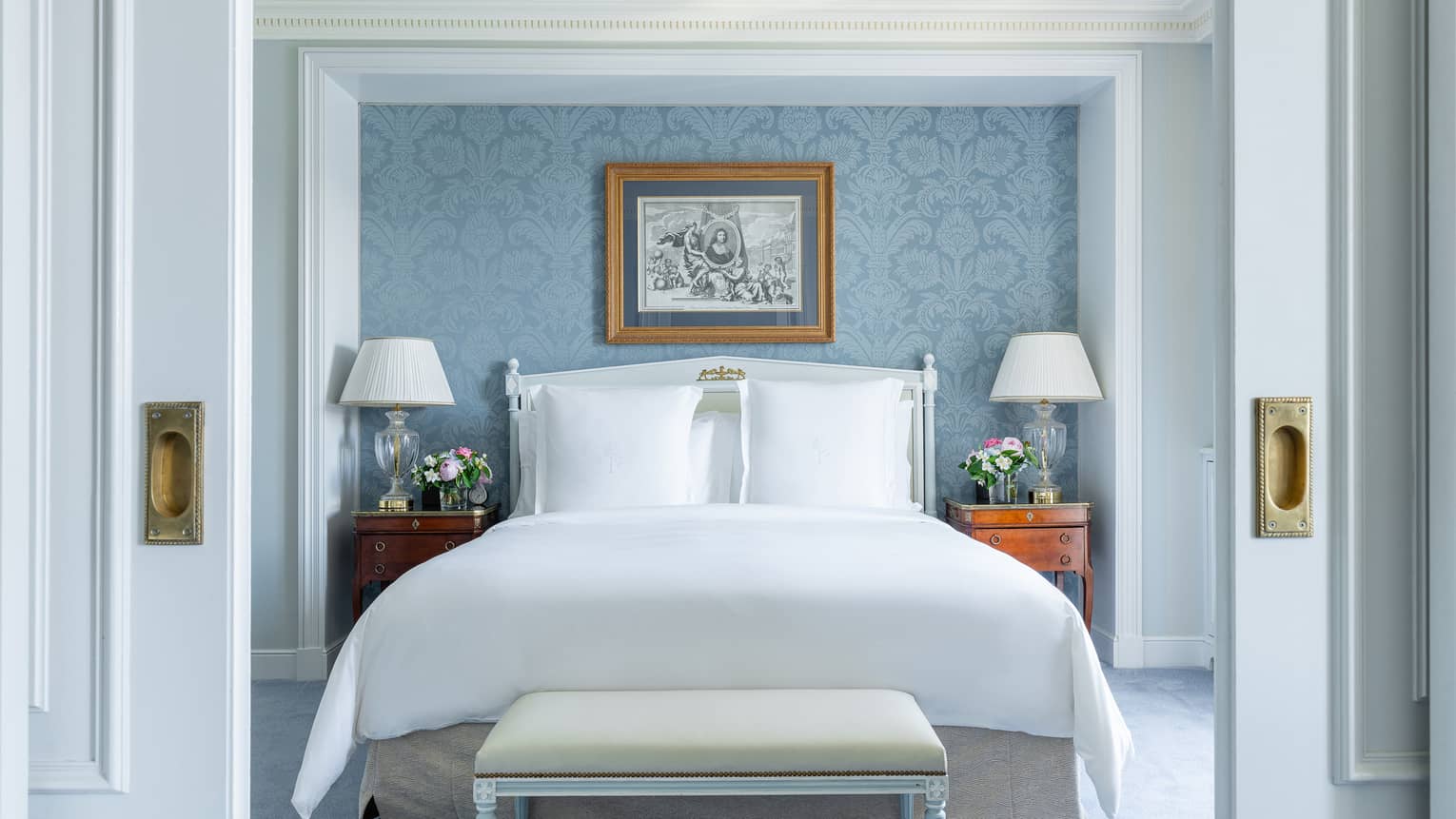 Luxury one-bedroom suite with a king bed and light blue wall paper accent wall at Four Seasons Hotel des Bergues, Geneva