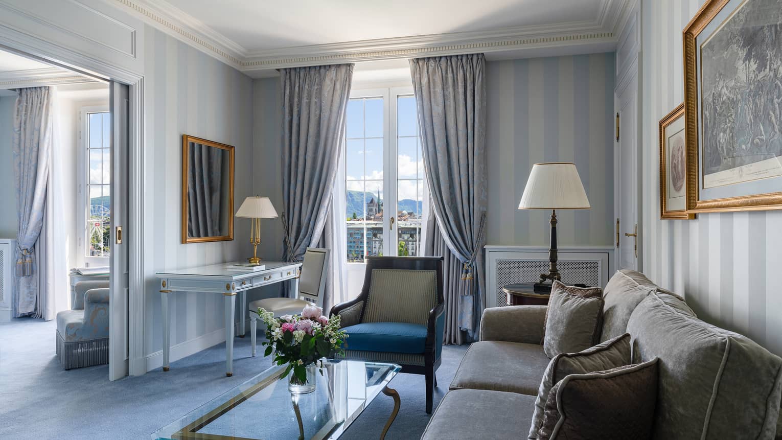 Hotel suite living room with sofa, arm chair and desk, leading into a bedroom, at Four Seasons Hotel des Bergues, Geneva