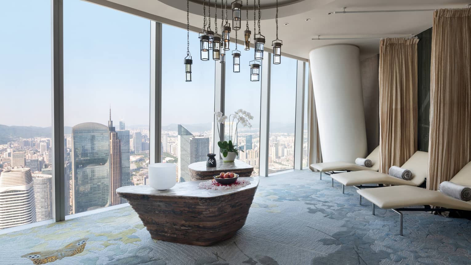 Large soaking tub filled with flower petals overlooking the cityscape from floor-to-ceiling windows