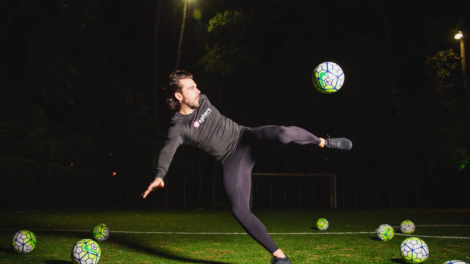 POWA by sphere session, Michael Chabala kicks soccer ball in mid-air on field with multiple balls at night