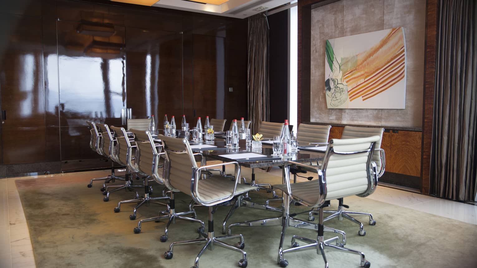 Meeting room with boardroom table, white leather swivel chairs and modern art painting