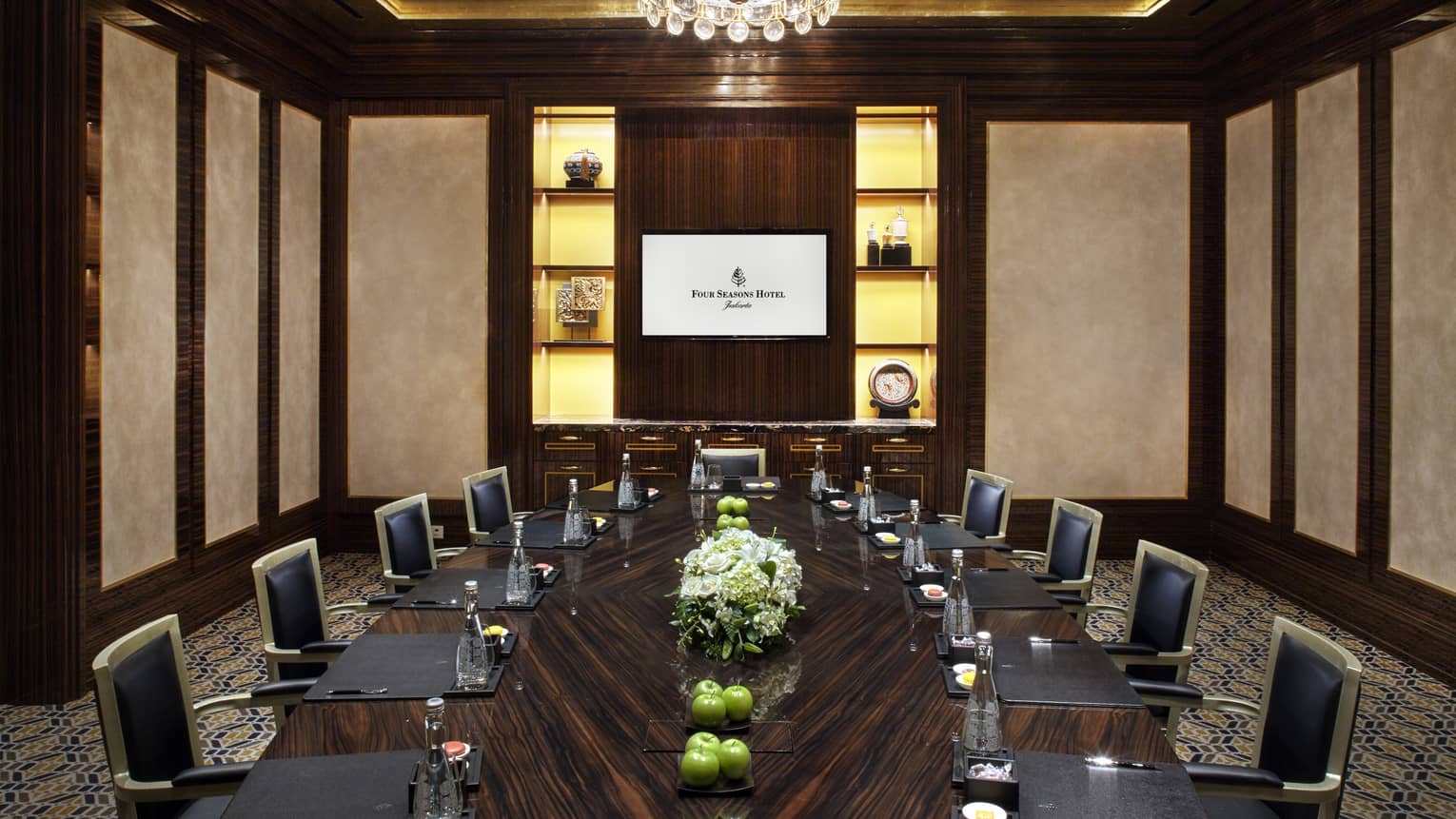 Meeting room with large wood boardroom table lined with executive chairs 